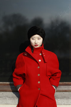 young chinese woman in red coat in front of window