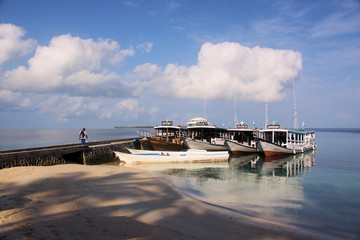Boats docked near a beach reflected in calm water
