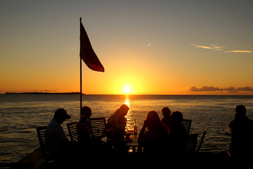 Friends at table watching sunset over the ocean 