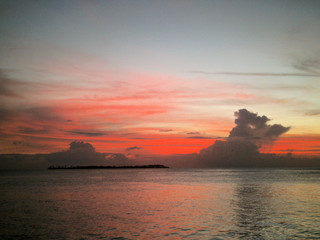 Bold red sky behind clouds in the ocean 
