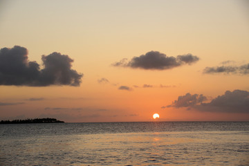 Naklejka na ściany i meble Sun setting on horizon over the ocean 