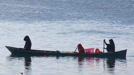 Women taking canoe into village in Indonesia. 