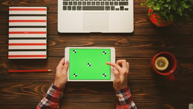 White tablet computer with green screen on the wooden table with red items. Flat lay. Top view. Chroma key. Tracking motion