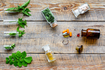 Herbal medicine. Leaves, bottles, pills on wooden background top view
