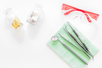 Dentists accessories. Tools, safety glasses and pills on white background top view copyspace
