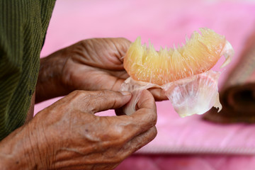 a  hand of old woman with a piece of pomelo