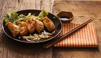 Gyoza in a plate / Gyoza in a black plate on an old wooden floor.Ready to eat