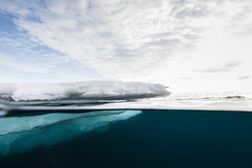 Above and below view of the ice floe edge on a partly cloudy day, east coast of Greenland.