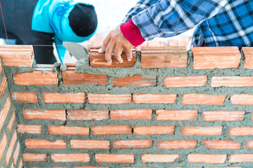 Construction worker build home by use cement mortar  to lay brick wall with a trowel follow vertical and horizontal guid line