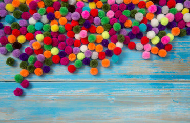colorful pom pom on blue wood background