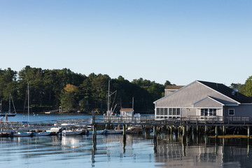 Fototapeta na wymiar Boothbay Harbor Marina with sailboats and motorboats docked. A cloudless blue sky is above and provides copy space.