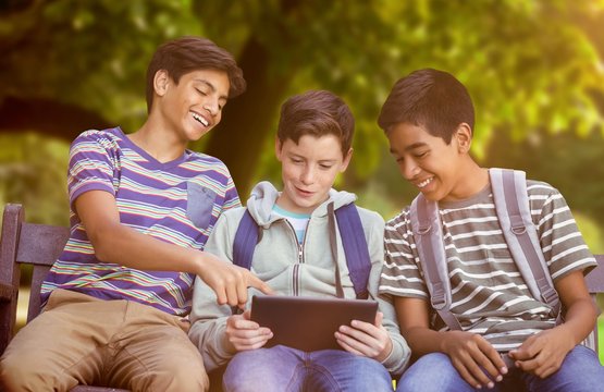 Composite image of boy with friends using digital tablet on