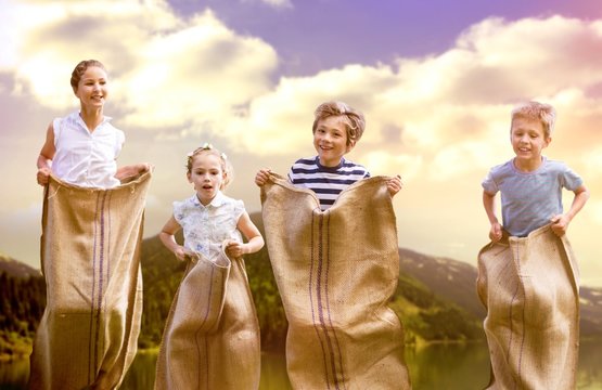 Composite image of friends playing sack race