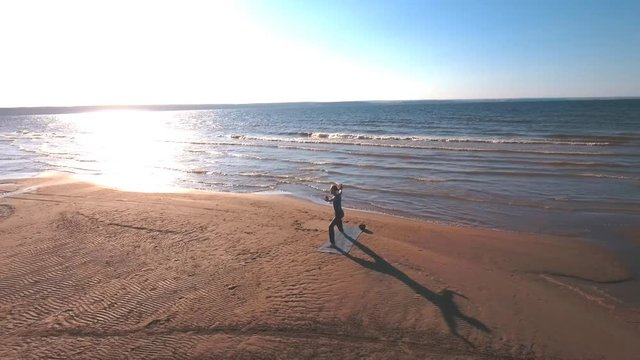 aerial view on a man does yoga on the beach at sunset