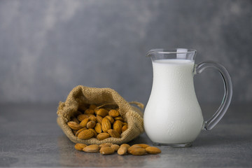 almond milk in jar with almonds in sackcloth on concrete background