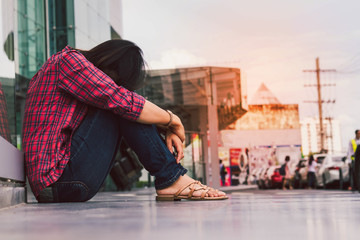 an Asia woman sitting on the floor in the city with sadness and loneliness.