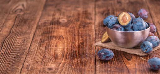 Fototapeta na wymiar Portion of Plums on wooden background, selective focus