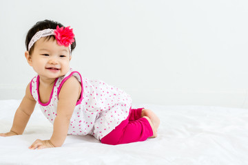 Portrait of adorable baby crawling on a white floor  with head band