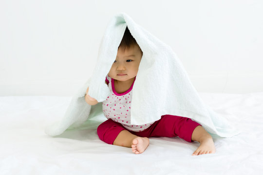 Portrait of adorable baby sitting with towel, indoors