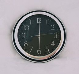 Black clock at six o'clock on white background. a mechanical or electrical device for measuring time, indicating hours, minutes, and sometimes seconds.