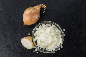 Some Chopped white onions on a dark slate slab