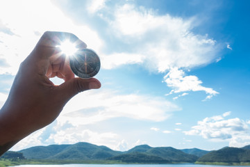 Hand with compass at mountain road at blue sky