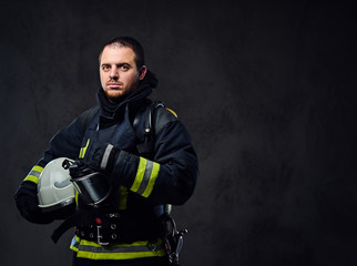 Fototapeta premium Firefighter dressed in uniform holds safety helmet.