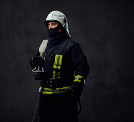 Firefighter in uniform holds fire hose.