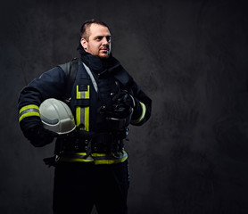 Fototapeta premium Firefighter dressed in uniform holds safety helmet.