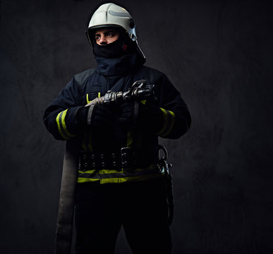 Firefighter in uniform holds fire hose.