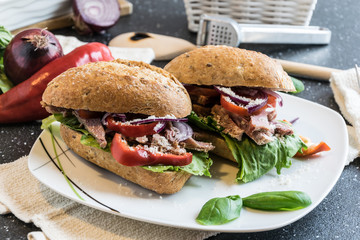 Homemade sandwich with pieces of grilled pork, vegetables and mayonnaise