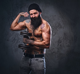Obraz na płótnie Canvas Shirtless muscular, bearded male holds dumbbell.