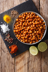 Snack of fried chickpeas with spices close-up in a bowl. Vertical top view