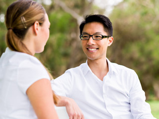 Portrait of smiling couple sitting in park and talking