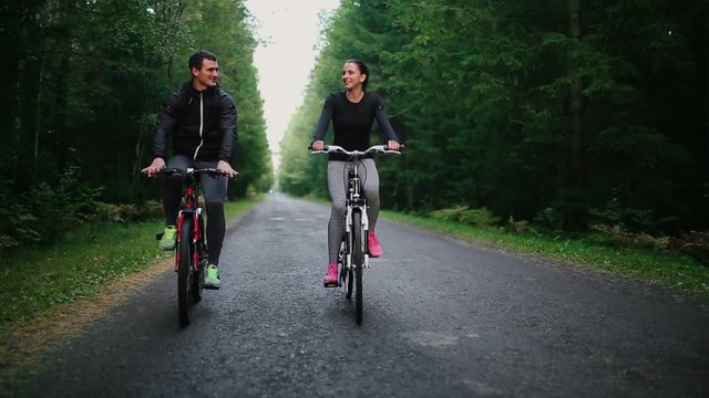 Happy couple riding bicycles outside, healthy lifestyle fun concept