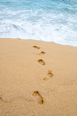 Footprints on the sea shore go into the water