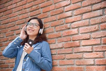 Fototapeta na wymiar Woman in blue shirt listening to the music with headphone.