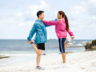 Young couple at the seaside doing exercises