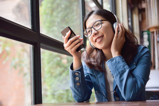 Asian woman listening to the music with headphone.