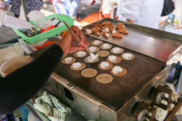 Local seller make small Thai crepe, Kanom Bueang at Sriyan market, Bangkok, Thailand
