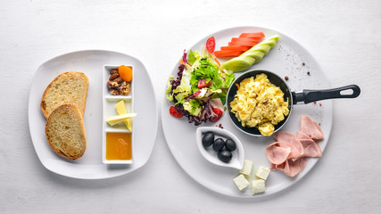 English breakfast. Eggs, olives, fresh vegetables, nuts, dried fruit and honey. Top view. Free space for text. On a wooden background.