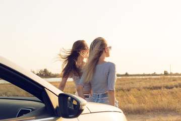 Two attractive young women near a convertible car