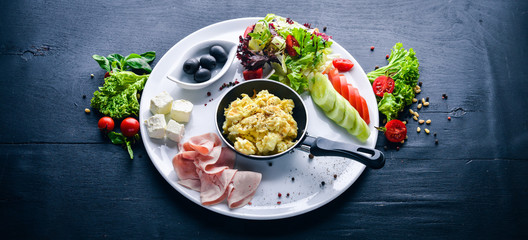 English breakfast. Eggs, olives, fresh vegetables, nuts, dried fruit and honey. Top view. Free space for text. On a wooden background.