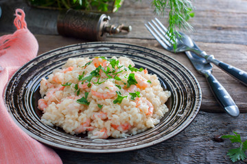 Italian risotto with shrimps on a table with fresh herbs, horizontal