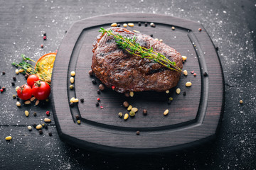 Veal steak with spices on the board. Top view. Free space for text. On a wooden background.