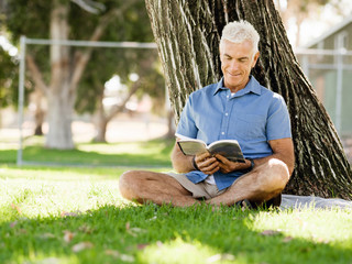 Senior man sittingin park while reading book