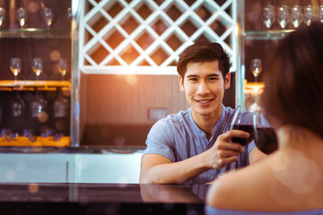 Young asian couple together man and woman clink glasses drink wine, cocktail in bar luxury party celebration clam relaxing in nightclub at pub, Closeup male and copy space the left.