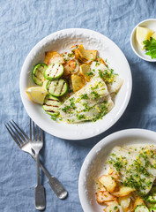 Pan roasted pollock with fried potatoes and grilled zucchini on a blue background, top view. Delicious lunch