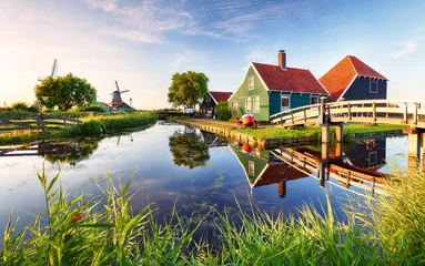 Foto auf Glas Traditionelle holländische Windmühle in der Nähe des Kanals. Niederlande, Landschaft bei Sonnenuntergang © TTstudio