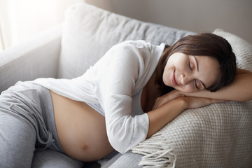 Young pregnant female sleeping dreaming about her house renovations and buying stuff online. Healthy nap for tired mother.